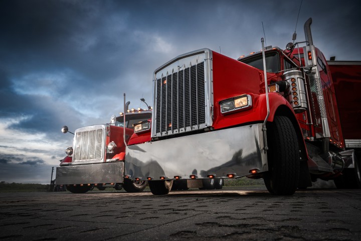 Two red semi trucks at dusk